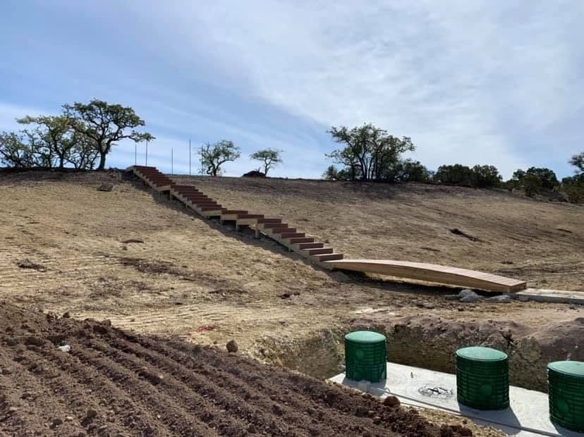 Long wooden staircase and walkway climbing a cleared hillside on a Central Texas ranch property