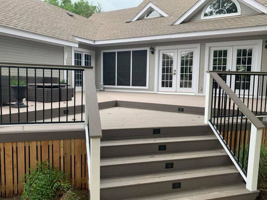 Two-level composite deck with black metal balusters, white posts, and lit stair risers