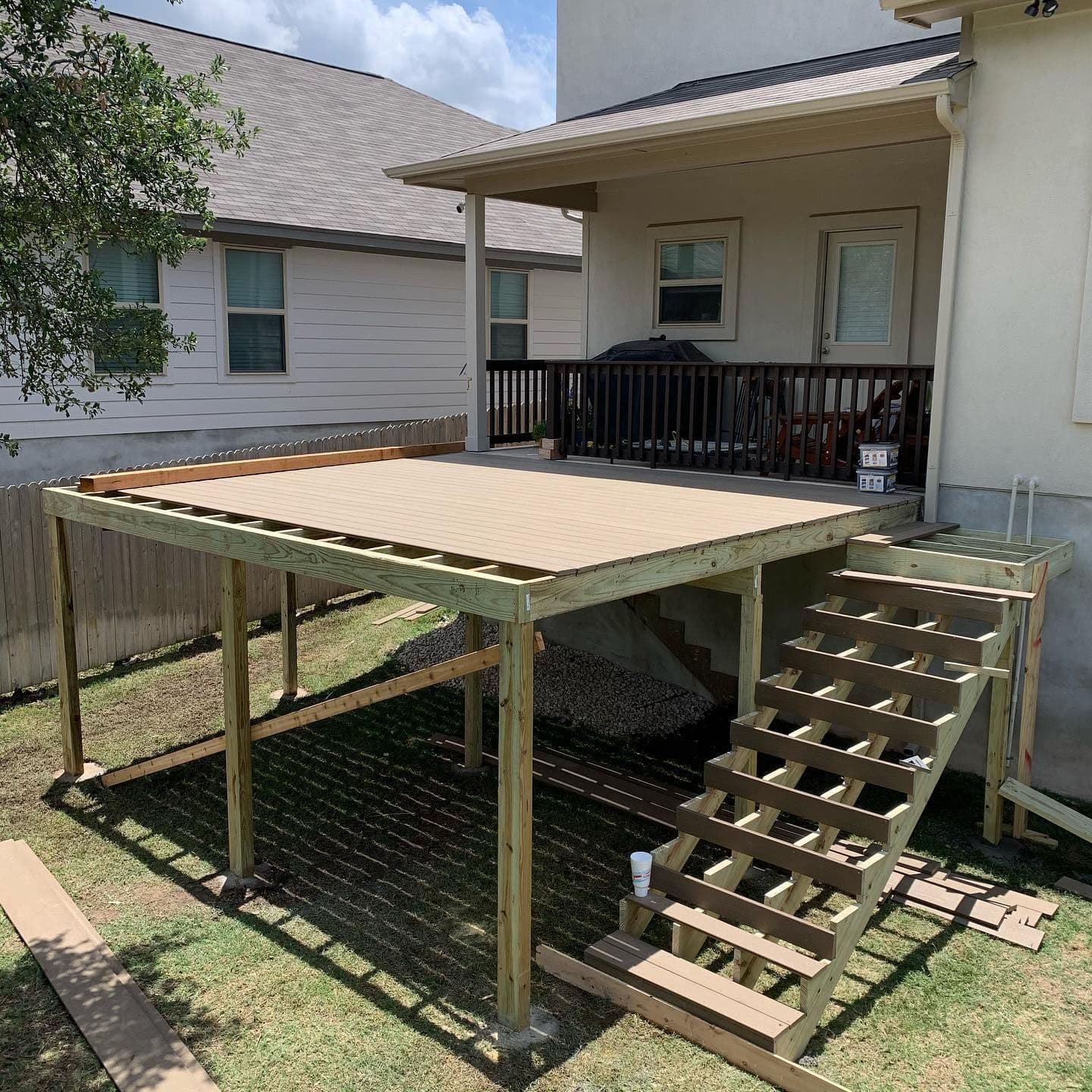 Elevated composite deck under construction with pressure-treated framing and a new stair run