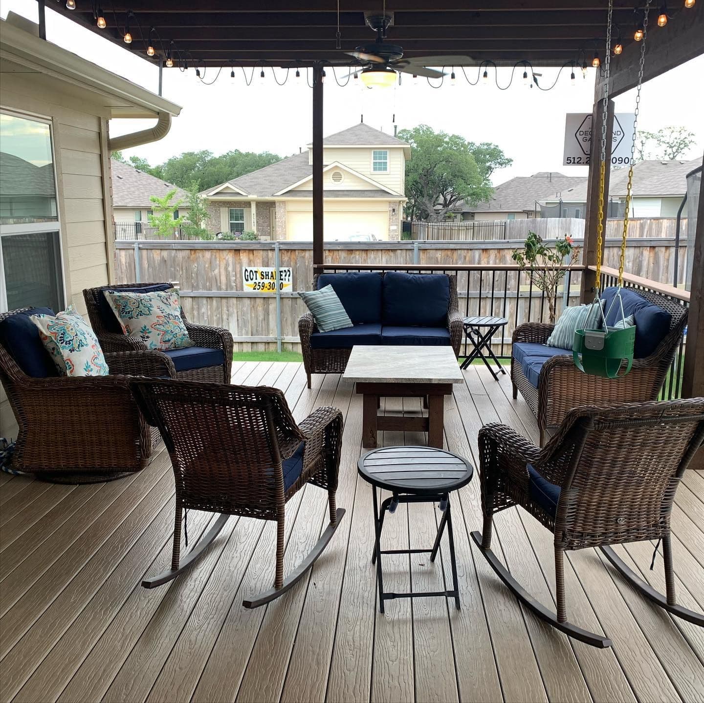 Covered composite deck with a ceiling fan, string lights, porch swing, and wicker seating
