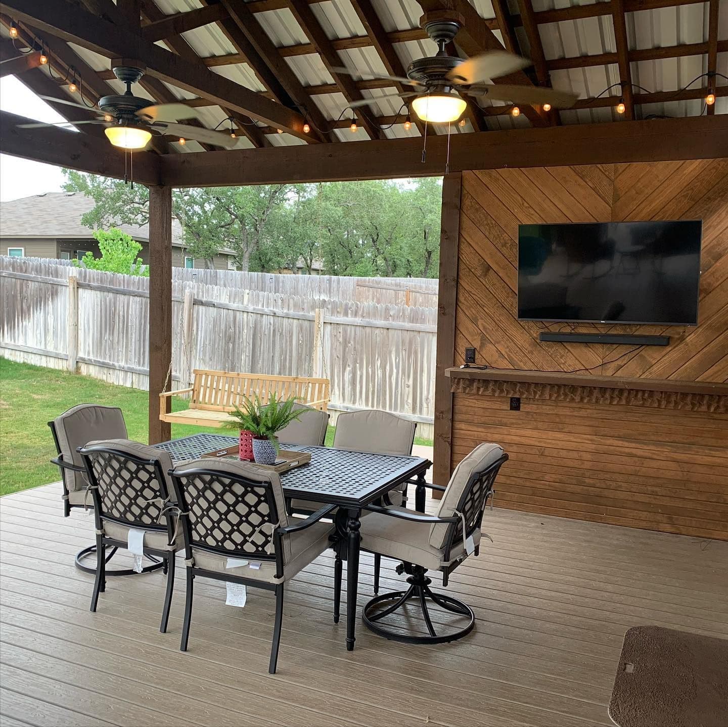 Covered deck with metal roof, twin ceiling fans, and a diagonal cedar TV accent wall