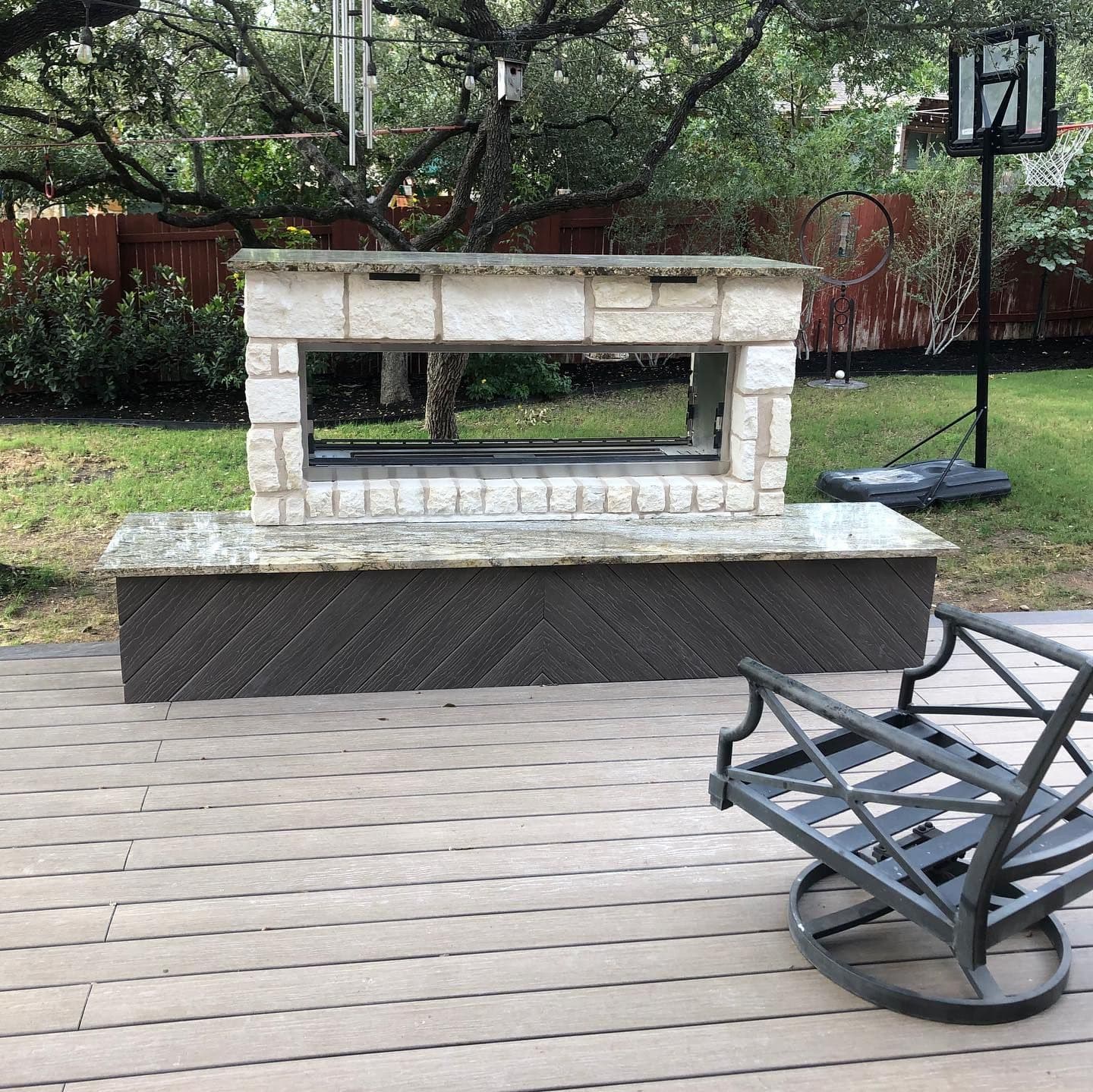 See-through limestone fireplace with granite ledge on a herringbone composite base atop a deck
