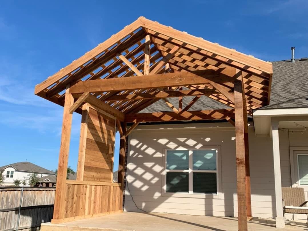 Cedar gable pergola with slatted roof and a solid privacy wall over a concrete patio