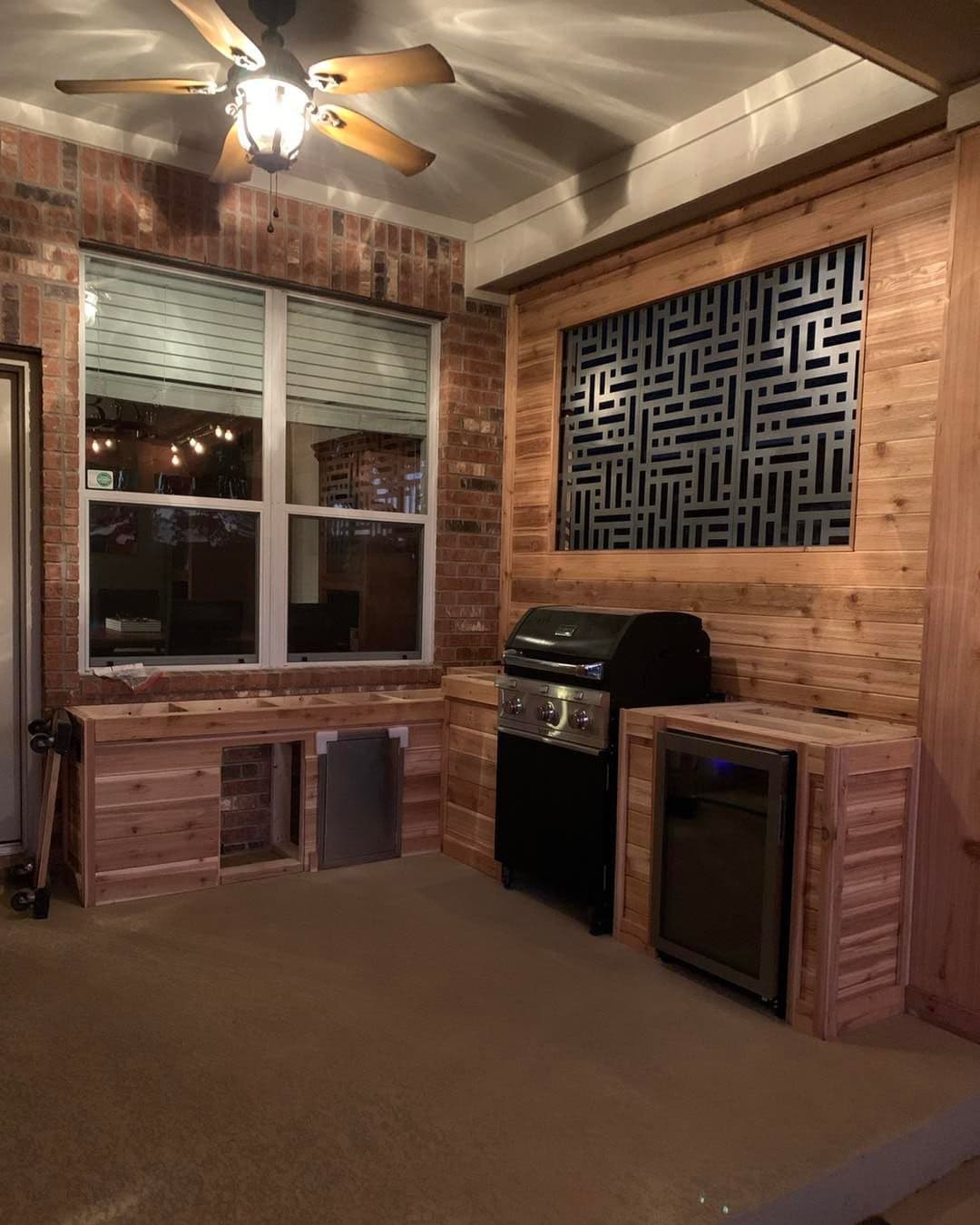 Cedar outdoor kitchen with built-in grill, beverage fridge, and decorative metal screen panel
