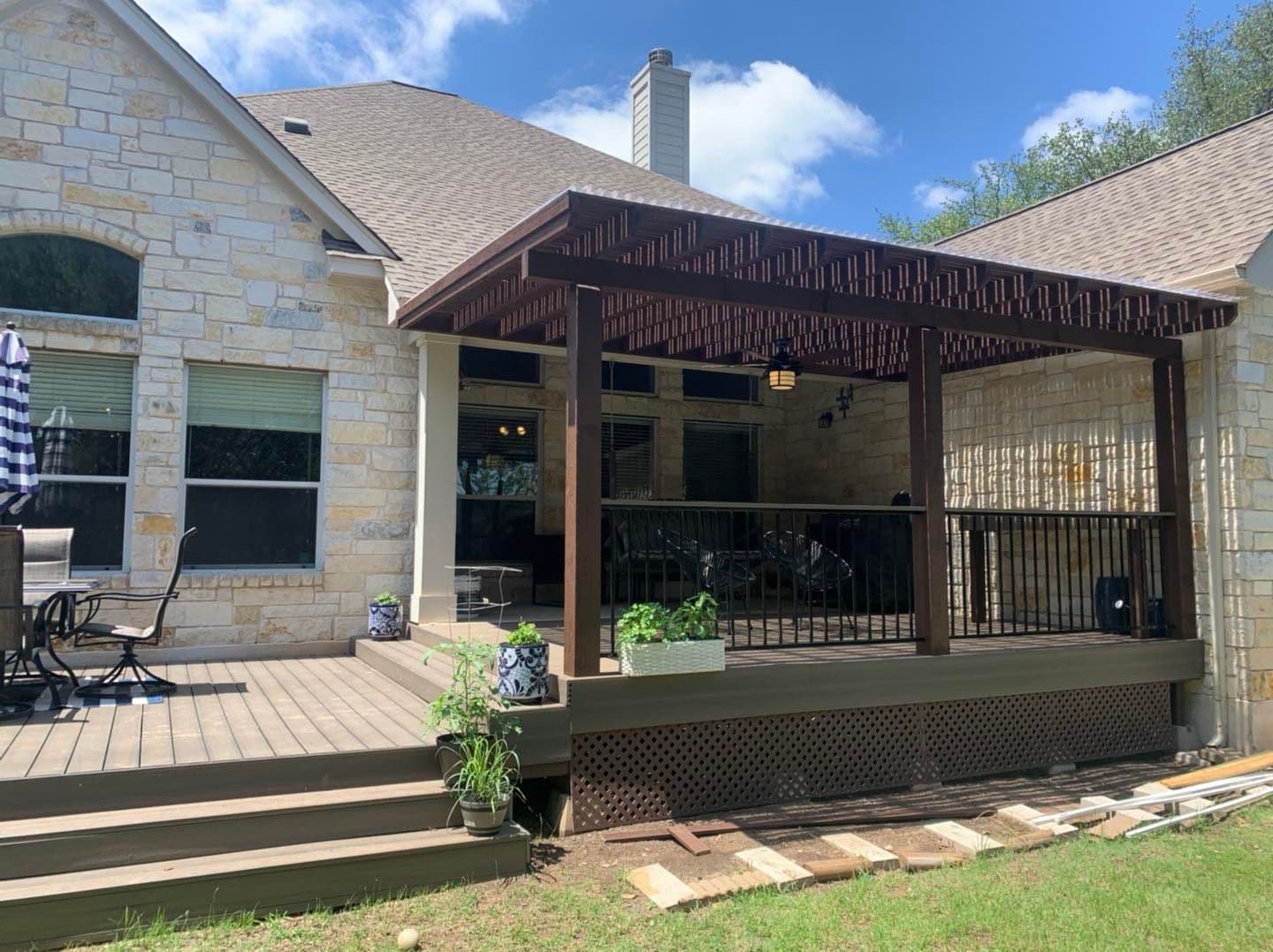 Stained pergola over a raised deck with black railing on an Austin area limestone home