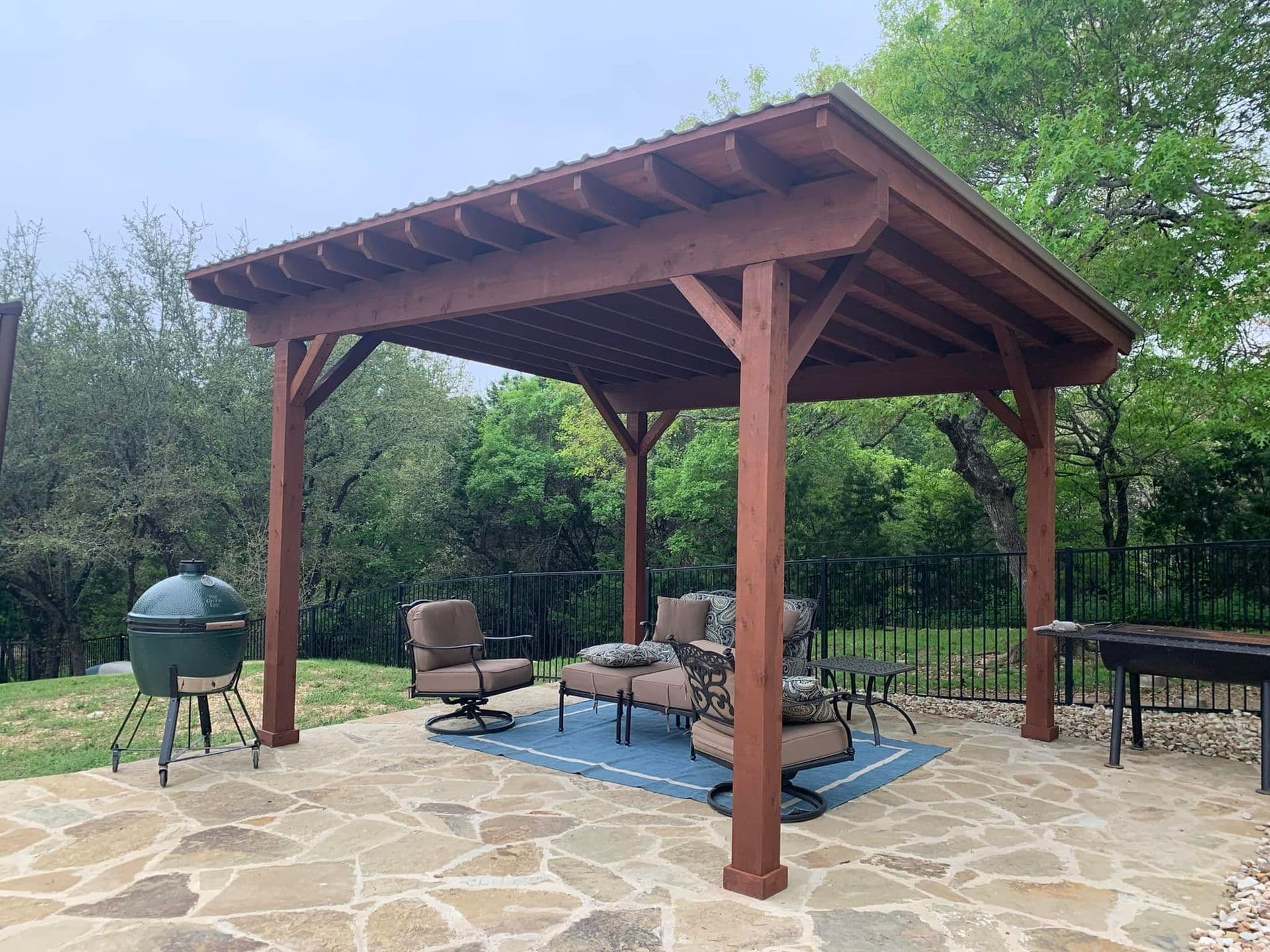 Stained cedar pavilion with metal roof over a flagstone patio in a Central Texas backyard
