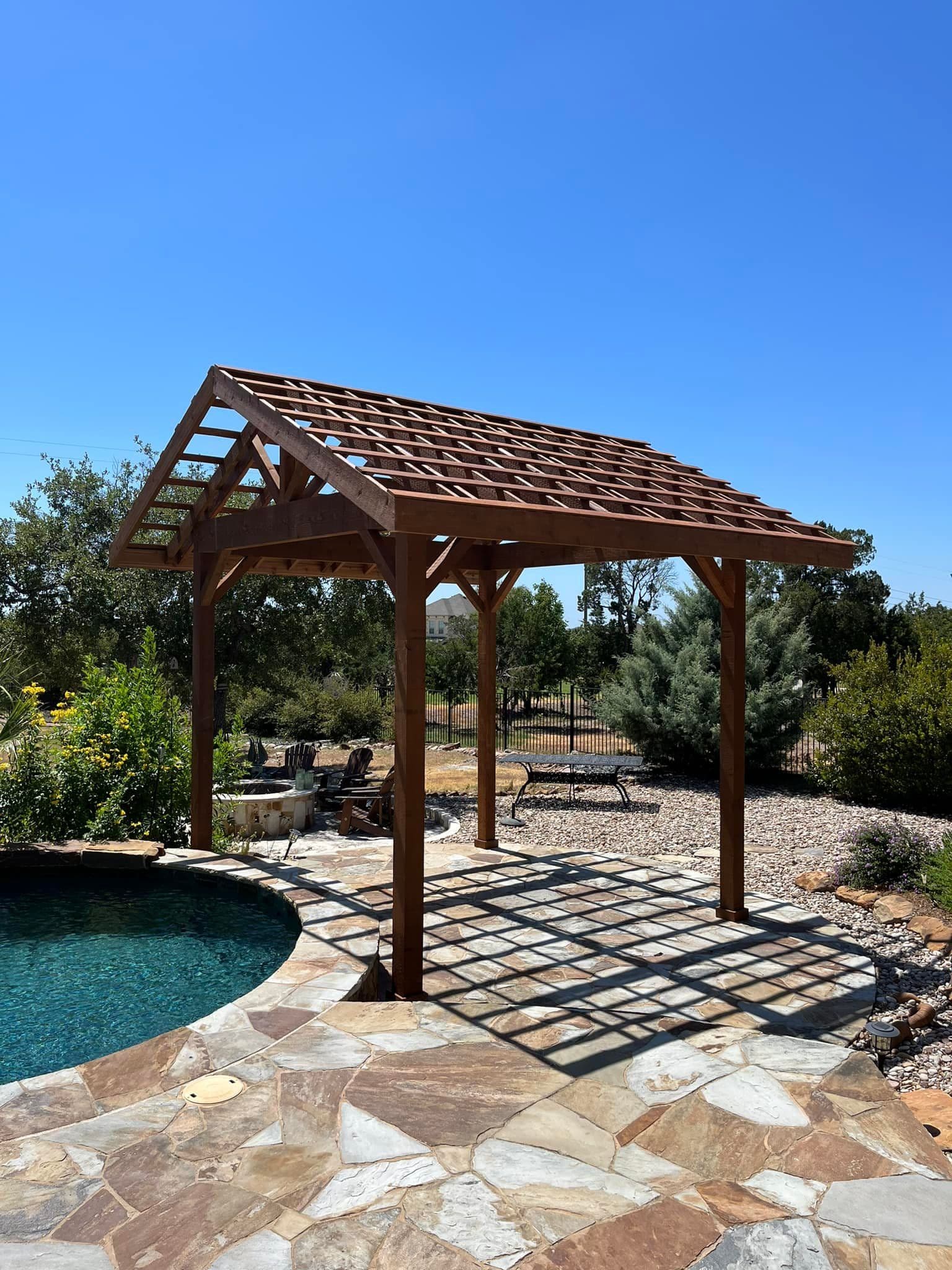 Small cedar gable pergola with slatted roof over a flagstone pool deck