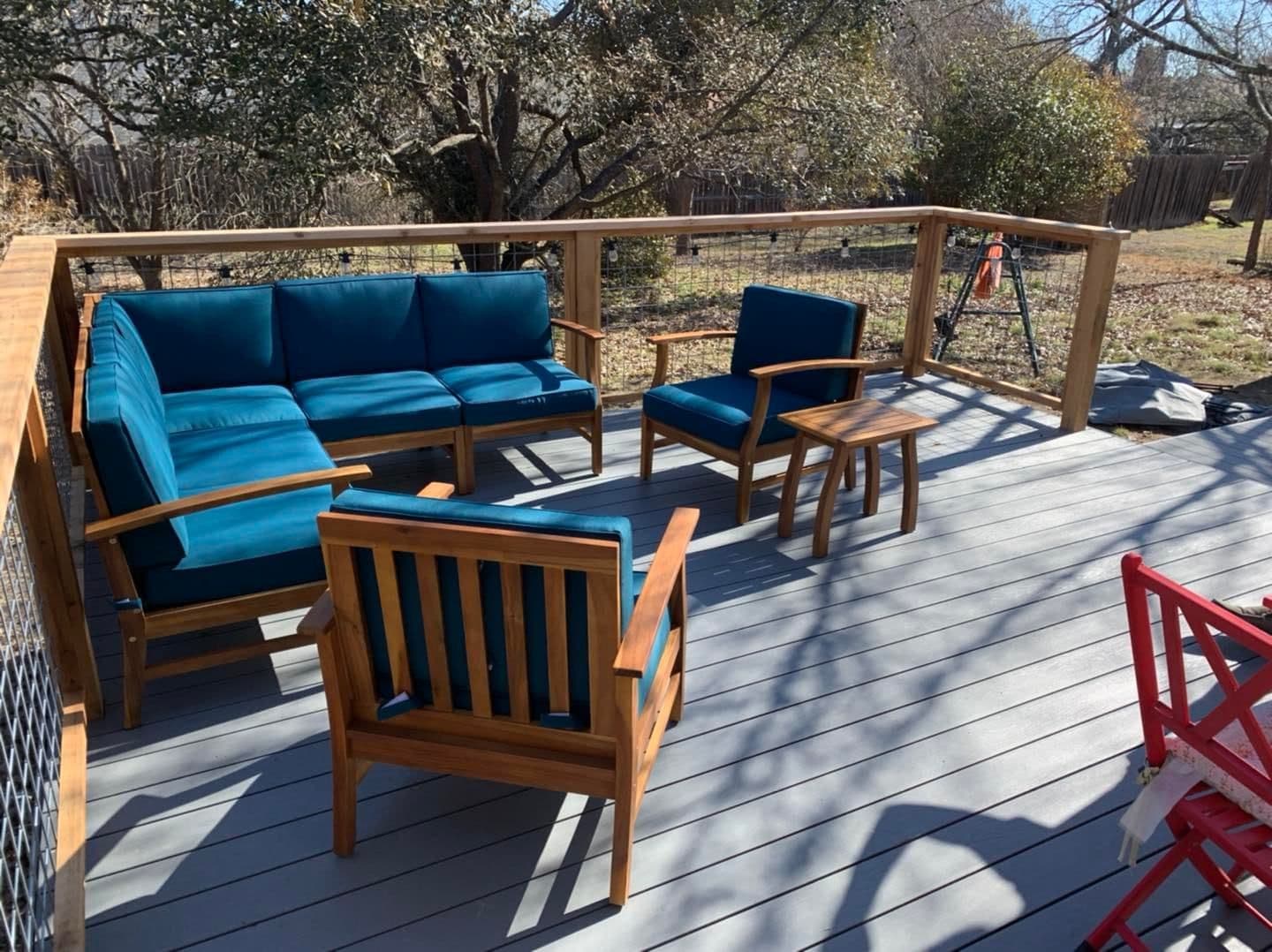 Gray composite deck with cedar framed welded wire railing and teal cushioned lounge seating