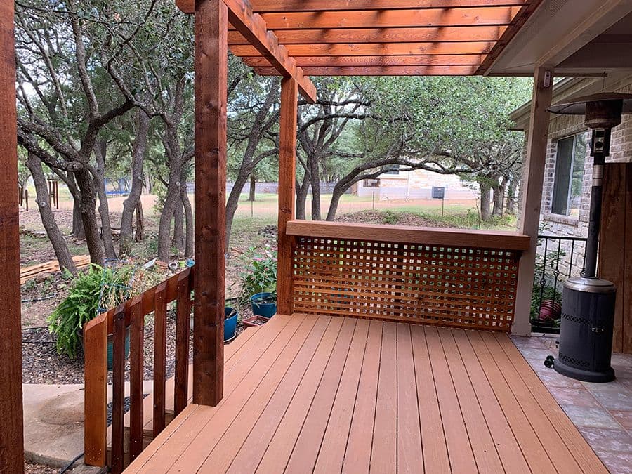 Cedar pergola over a composite deck with a square lattice privacy panel among live oaks